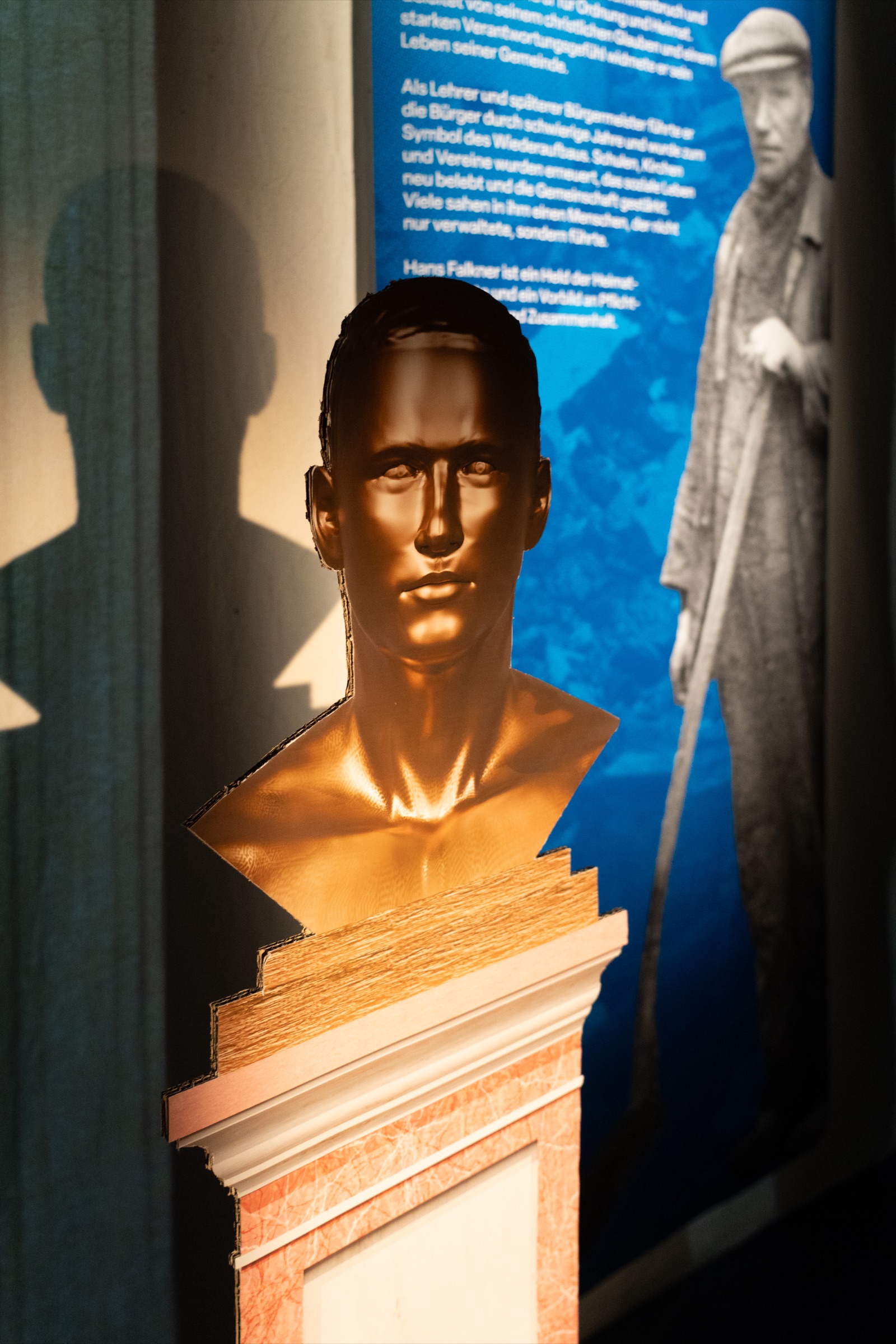 Bronze bust of Hans Falkner in front of a blue banner